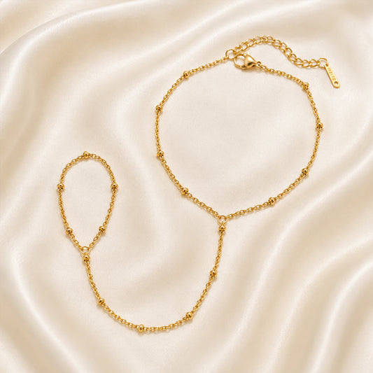 Gold handchain on a beige satin background