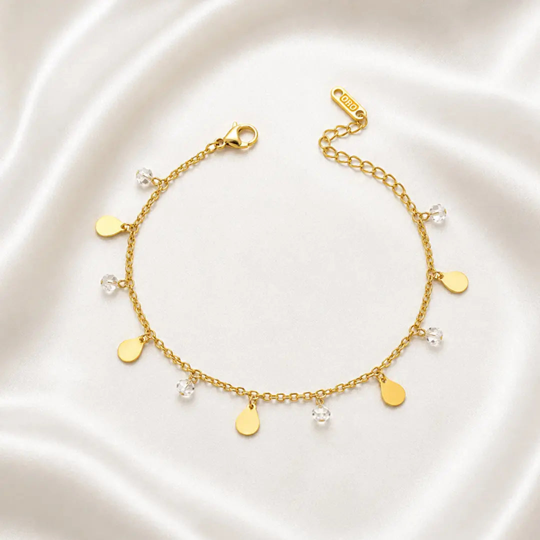 Gold bracelet with heart-shaped charms on a white satin background