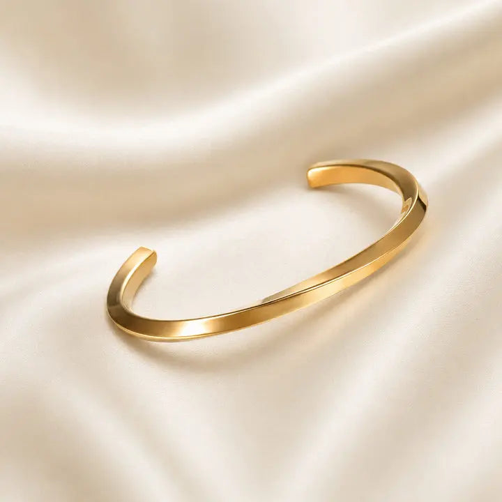 Gold bracelet on a beige satin background