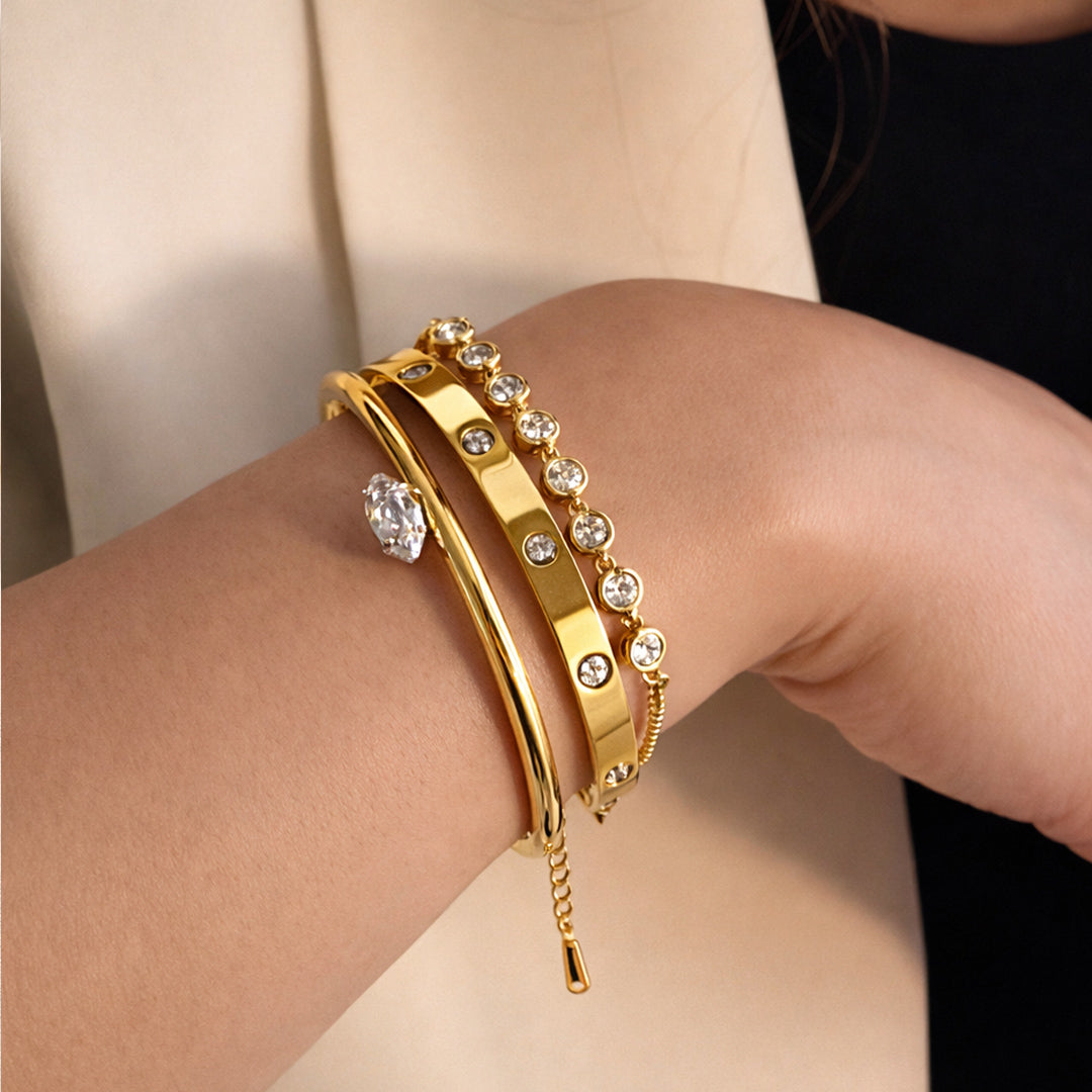 Close-up of a woman’s wrist wearing a gold-plated zircon bangle and bezel-set bracelet stack.