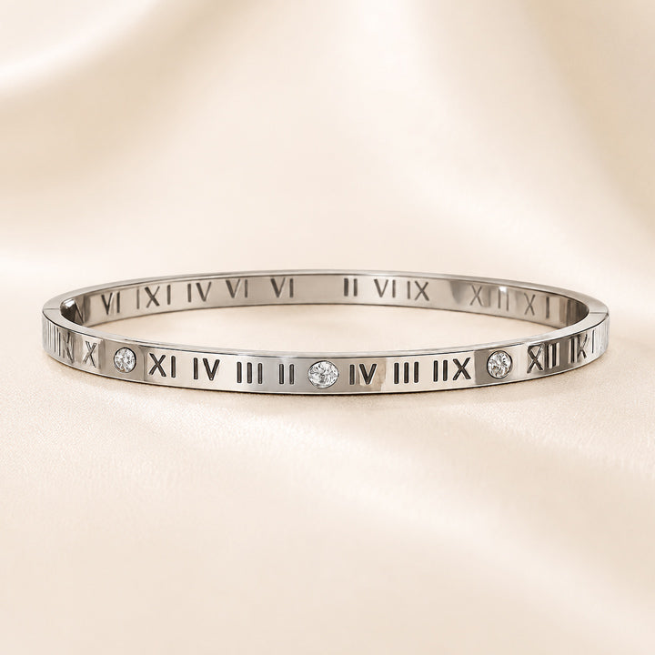 Silver bracelet with Roman numeral design on a beige background