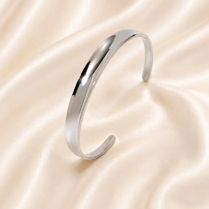 Silver bracelet on a soft, beige fabric background