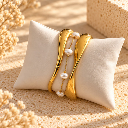 Gold sculptural bracelet stack with pearl-like chain bracelet on ivory cushion – OROR Parure