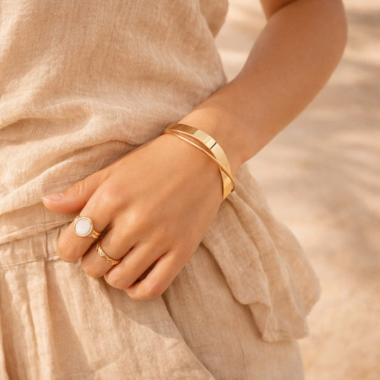 Gold cuff bangle with refined crisscross line, styled on wrist