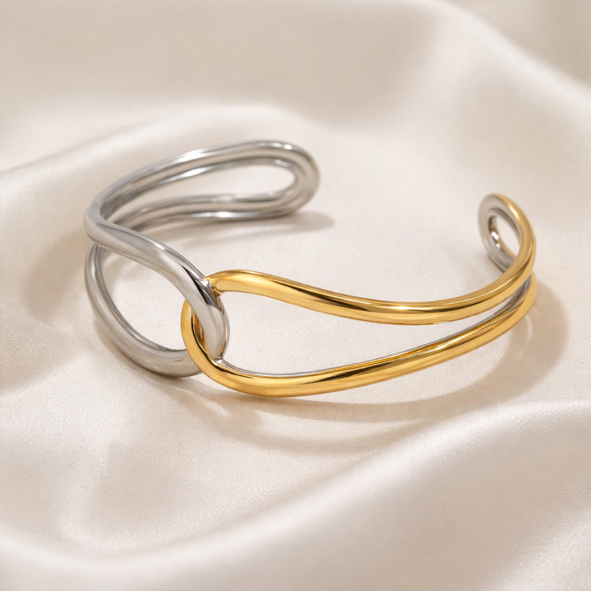 Double tone sculpted open cuff bracelet with interwoven silver and gold curves on ivory fabric