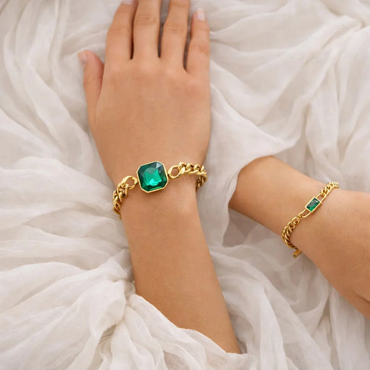 Emerald faceted gold chain bracelet styled on wrist, adjustable chain with polished emerald stone