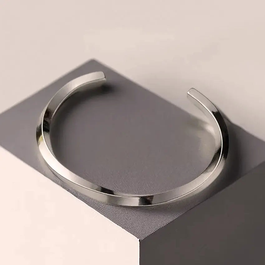 Minimal stainless steel open cuff bracelet on display, polished finish