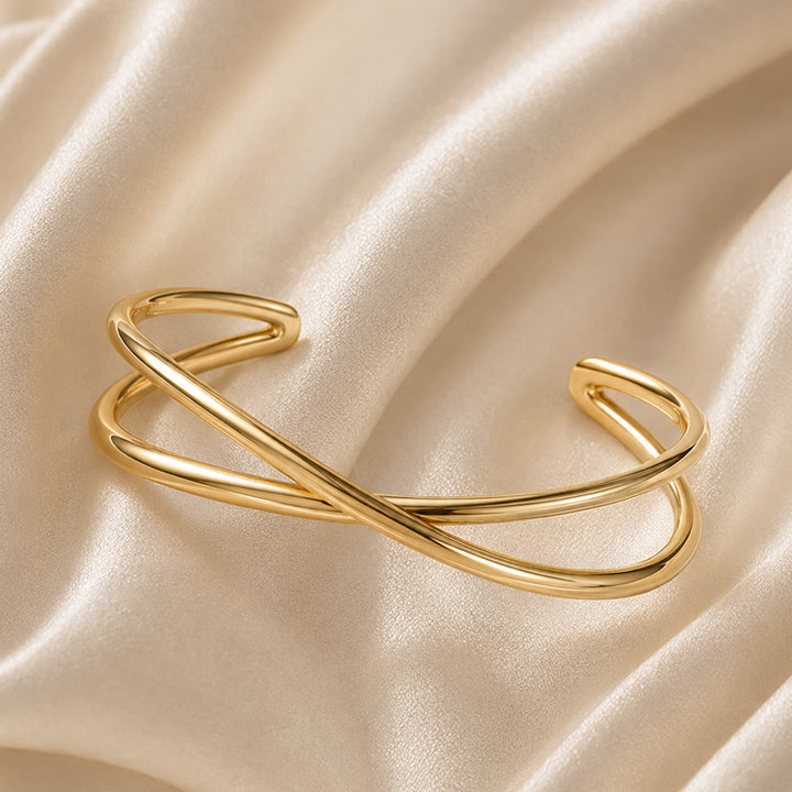 18K PVD gold crossover cuff bracelet on ivory satin background