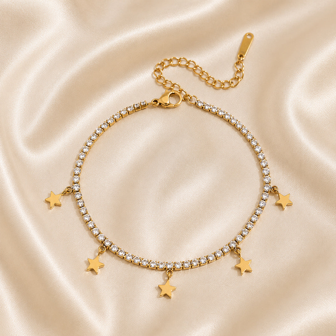 Gold bracelet with star charms on a satin background