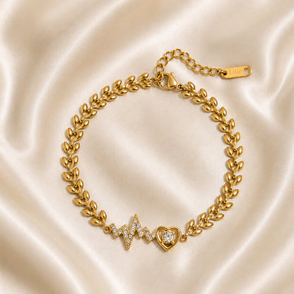 Gold bracelet with pavé heartbeat motif and heart charm displayed on ivory satin in OROR luxury styling.