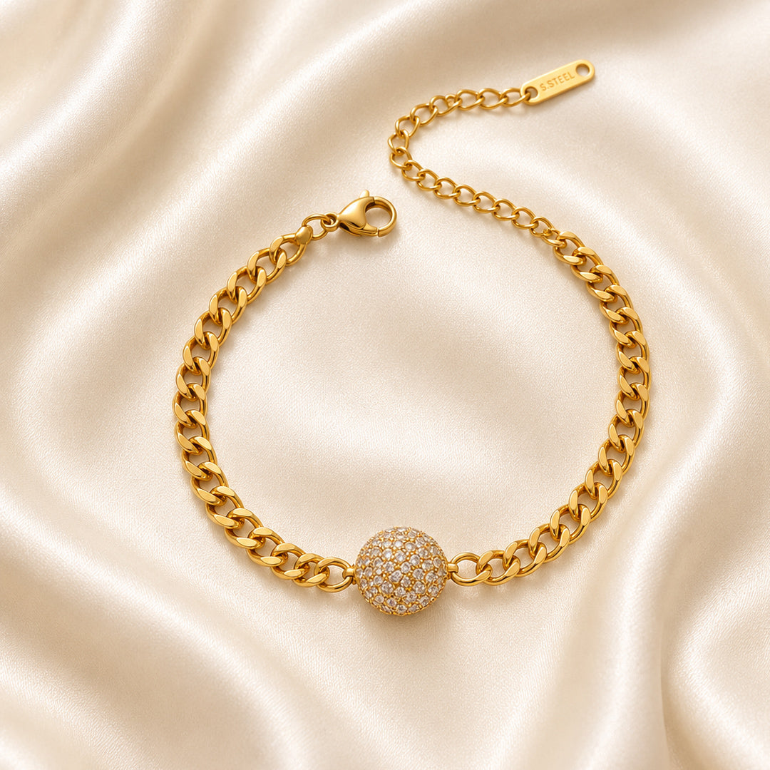 Gold curb chain bracelet with a pavé-set round centerpiece displayed on ivory satin in OROR luxury styling.