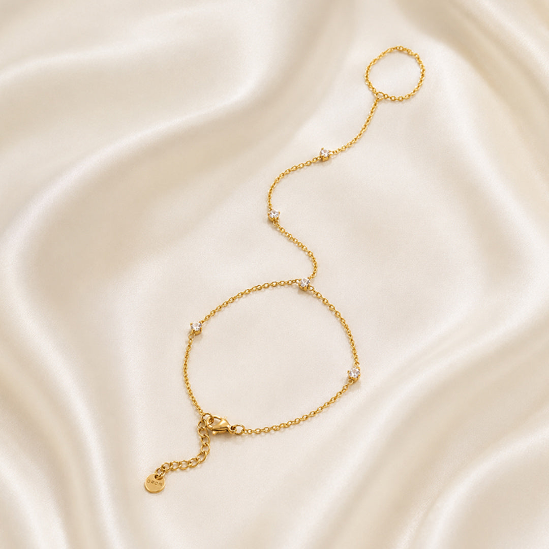 Gold handchain on a smooth, light-colored fabric background