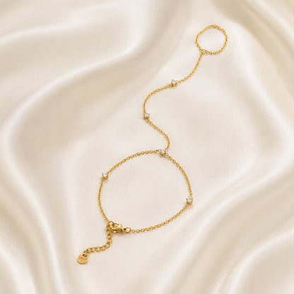 Gold handchain on a smooth, light-colored fabric background