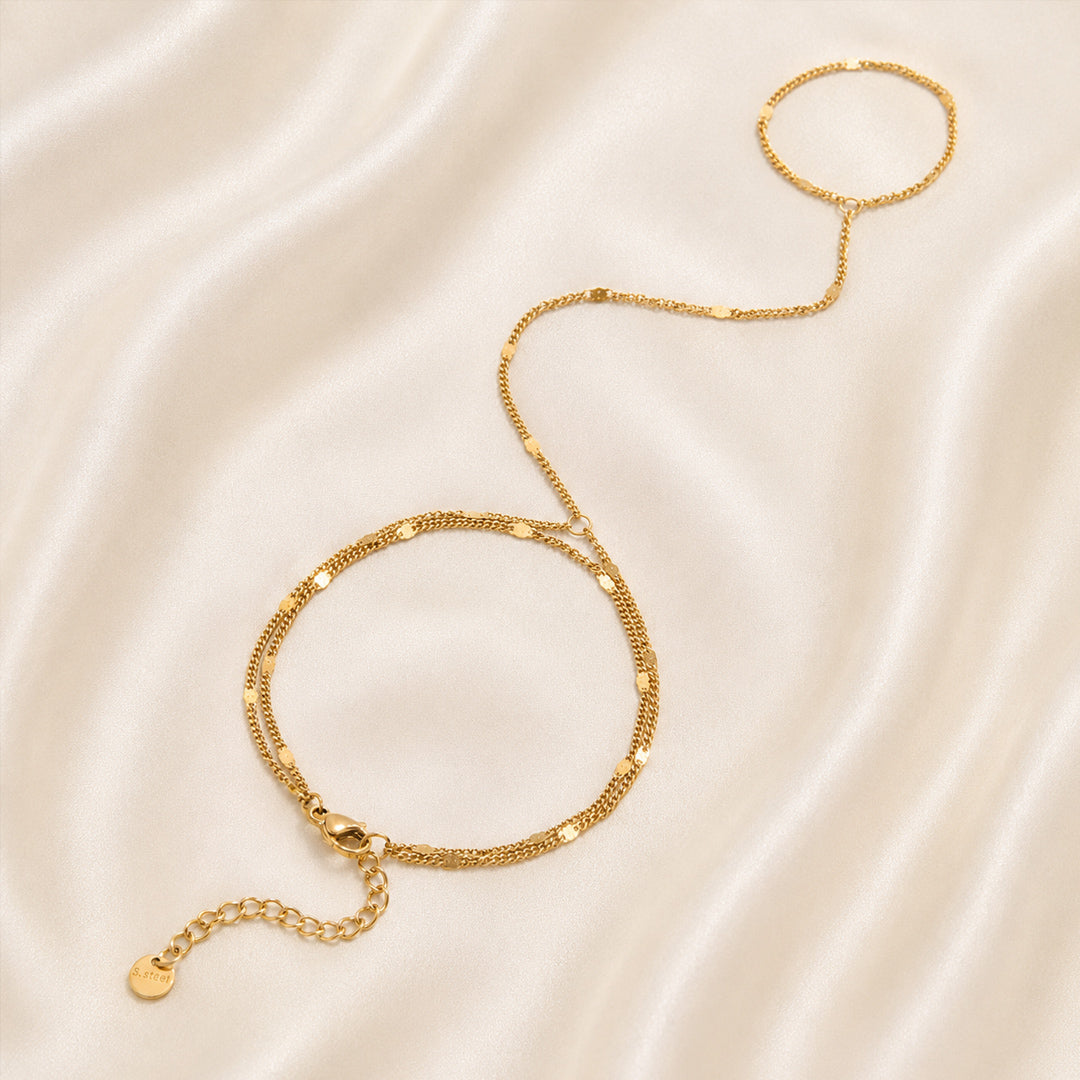 Gold handchain on a beige satin background
