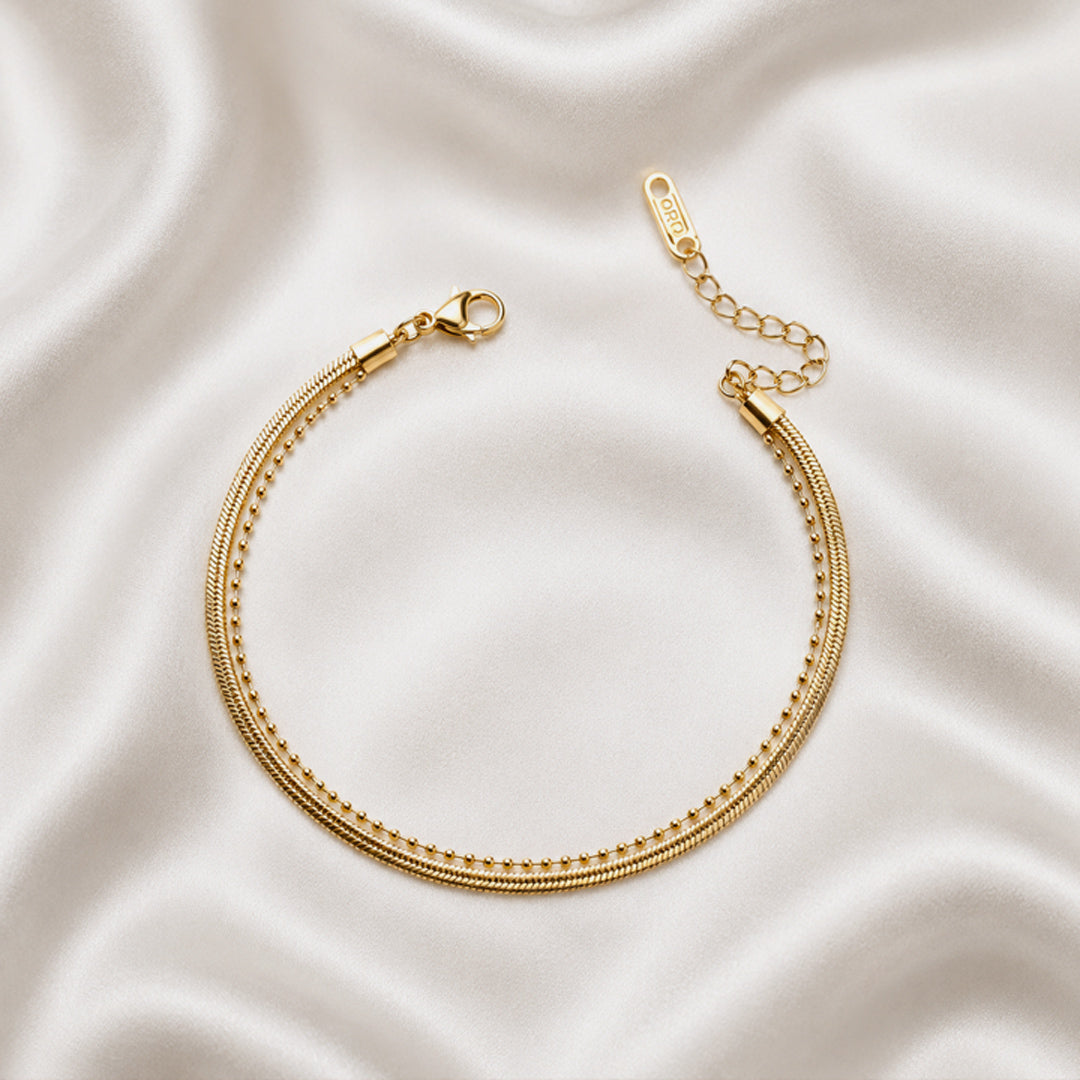 Aurea Anklet featuring layered 18K PVD gold plated snake and beaded chains on a woman's ankle.
