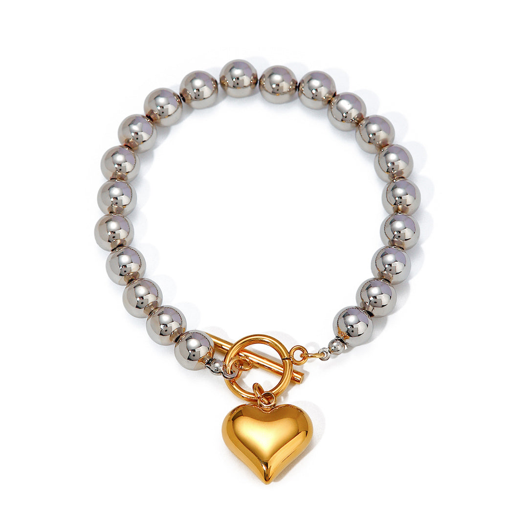 Bracelet with silver beads and a gold heart charm on a white background