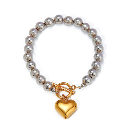 Bracelet with silver beads and a gold heart charm on a white background