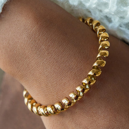 Gold spiral cuff bracelet with sculptural open wrapped design in polished stainless steel