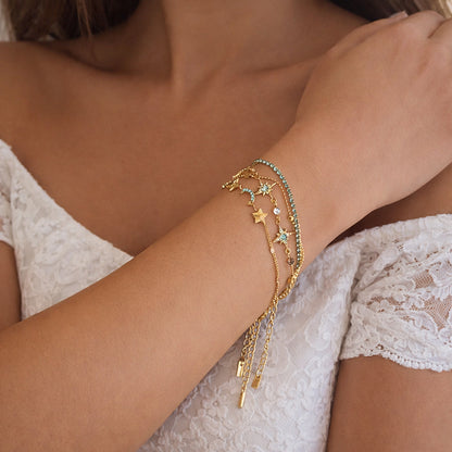 Gold-plated layered chain bracelet stack on wrist, turquoise zircon details