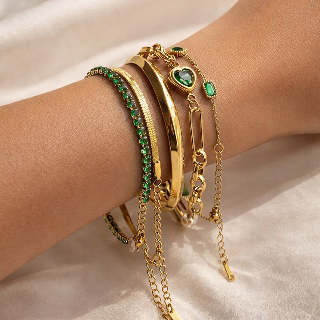 Woman wearing Emerald Reverie Stack featuring five gold bracelets with emerald gemstone accents and polished gold bangles.