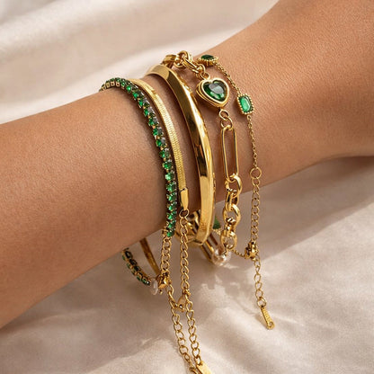 Woman wearing Emerald Reverie Stack featuring five gold bracelets with emerald gemstone accents and polished gold bangles.