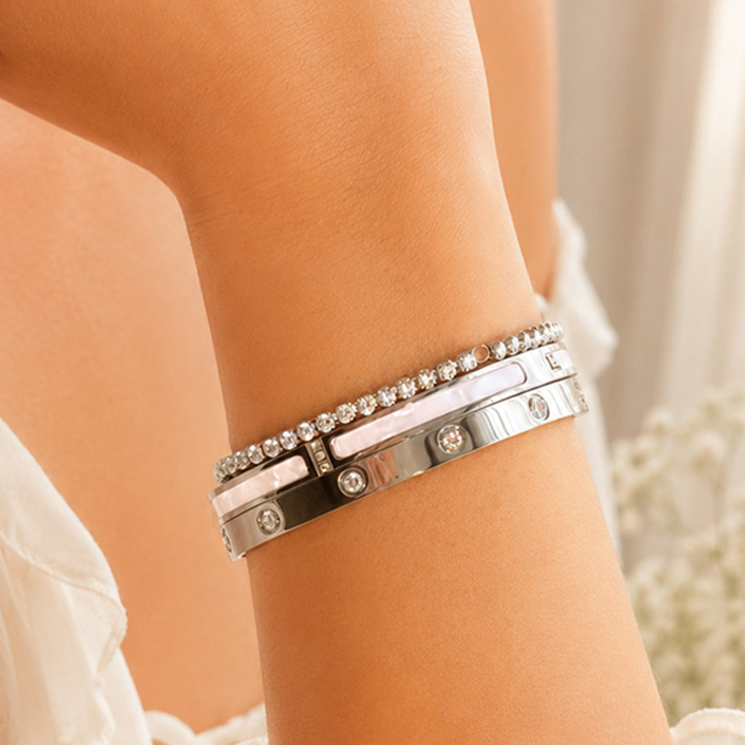 Young woman wearing the Éclipse Polished Stainless Steel stack featuring white enamel bangles and a Zirconia tennis bracelet in a luxury editorial setting.