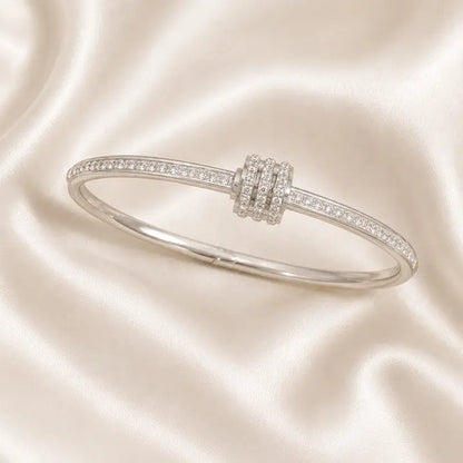 Aurélie Pavé Stainless Steel Bangle featuring pavé zircon detailing and sculptural multi-ring centerpiece displayed on ivory satin.