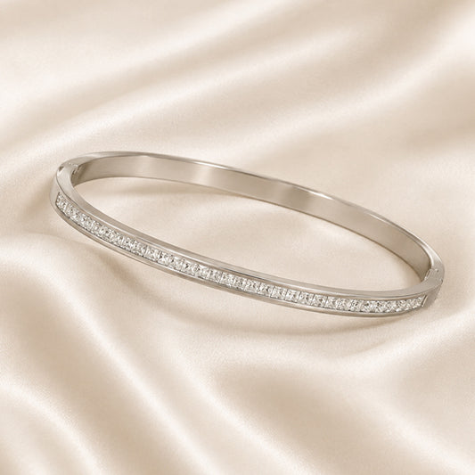 Éclat Pavé Stainless Steel Bangle featuring continuous zircon detailing displayed on ivory satin.