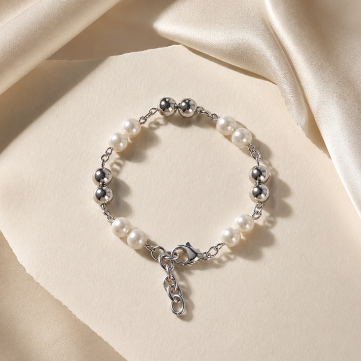 Pearl and silver bracelet on a beige fabric background