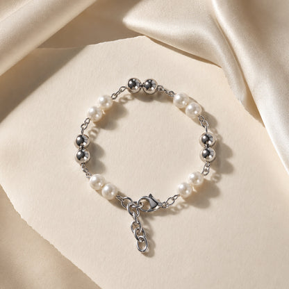 Pearl and silver bracelet on a beige fabric background