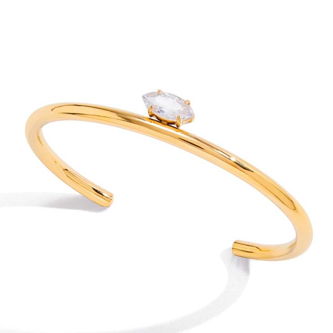 Gold bracelet with a clear gemstone on a white background