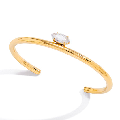 Gold bracelet with a clear gemstone on a white background