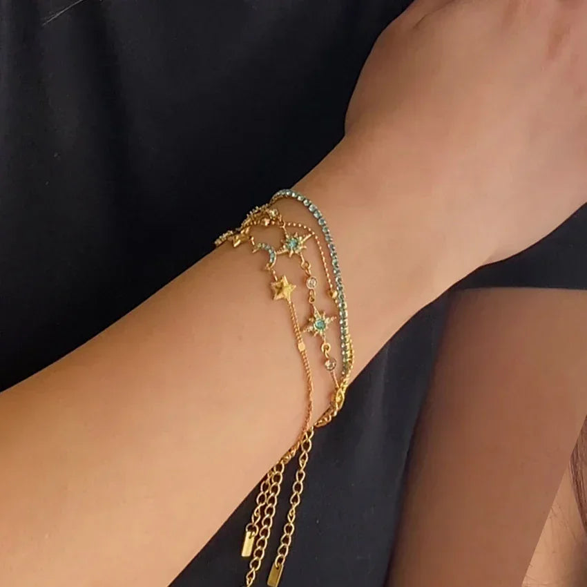 Gold-plated layered chain bracelet stack on wrist, turquoise zircon details
