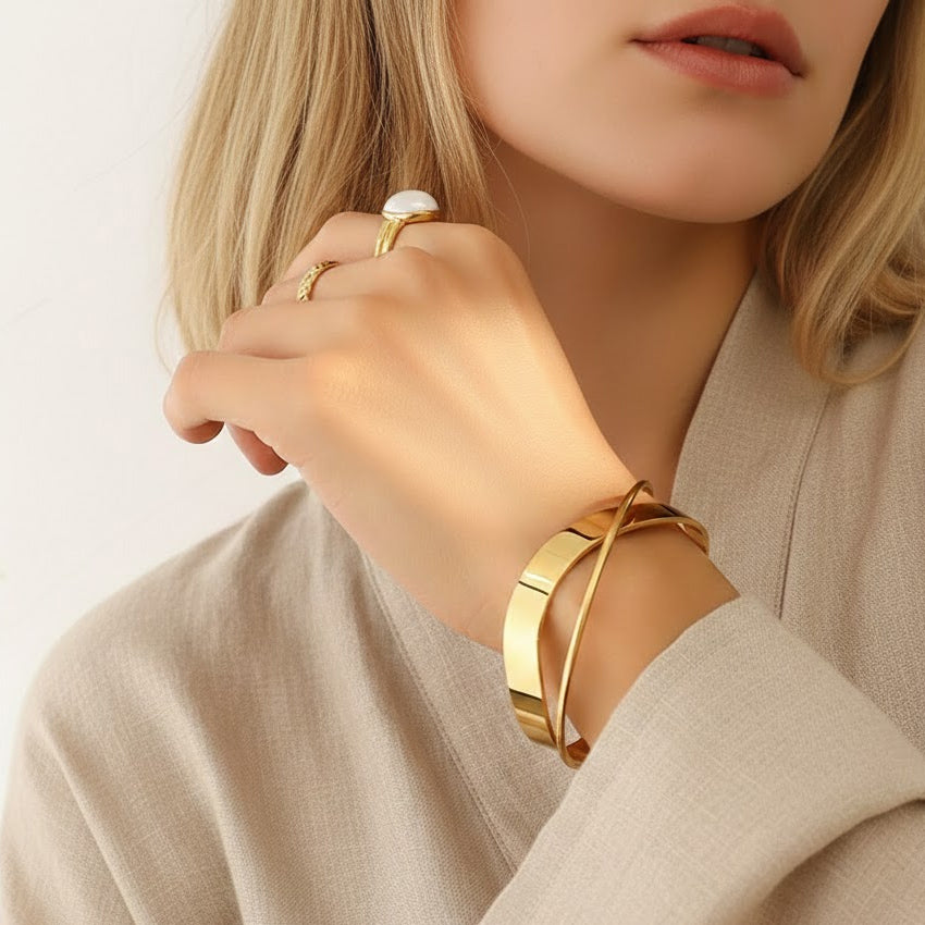 Crisscross gold PVD cuff bangle on wrist, polished wide band design