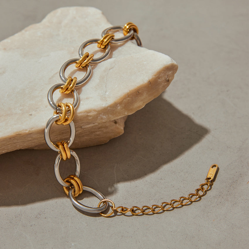Double tone interlock chain bracelet with oversized silver-tone oval links and gold accents on stone surface
