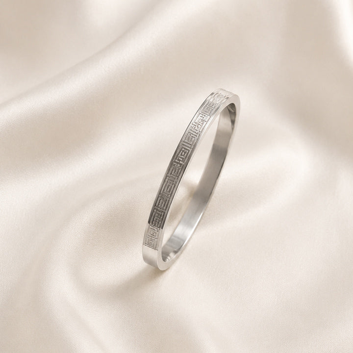 Silver ring with engraved design on a satin surface