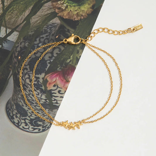 Celeste triple star double-chain gold-plated bracelet with three sculpted star motifs, flat lay
