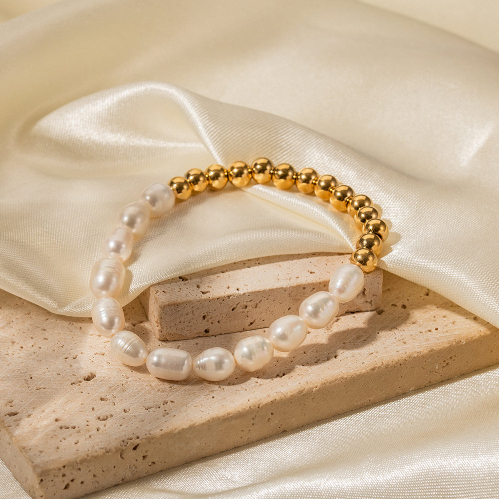 Freshwater pearl and gold sphere stretch bracelet on stone surface