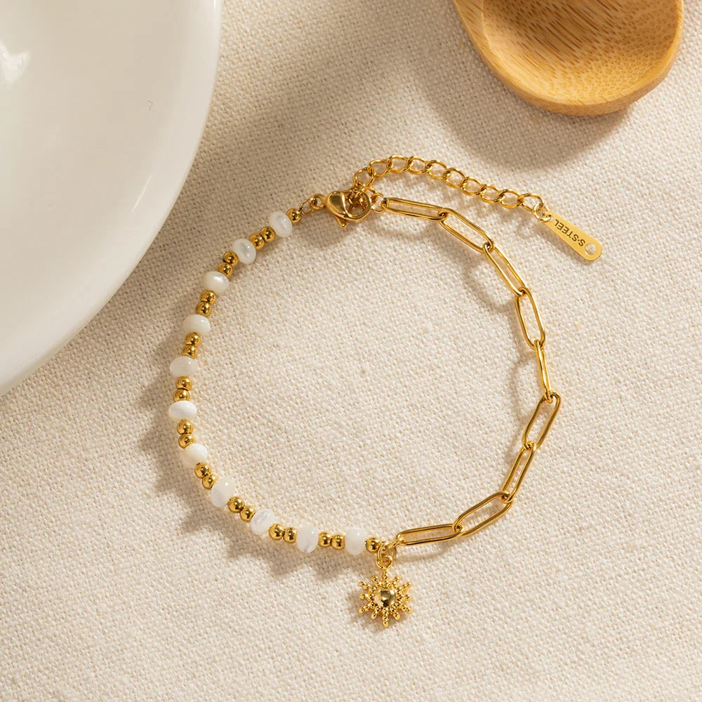 OROR sun charm chain bracelet with pearl-effect beads and PVD gold plating on ivory background