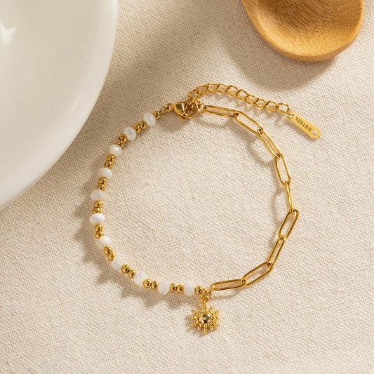 OROR sun charm chain bracelet with pearl-effect beads and PVD gold plating on ivory background