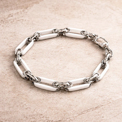 White ceramic chain bracelet with polished stainless steel connectors on stone surface