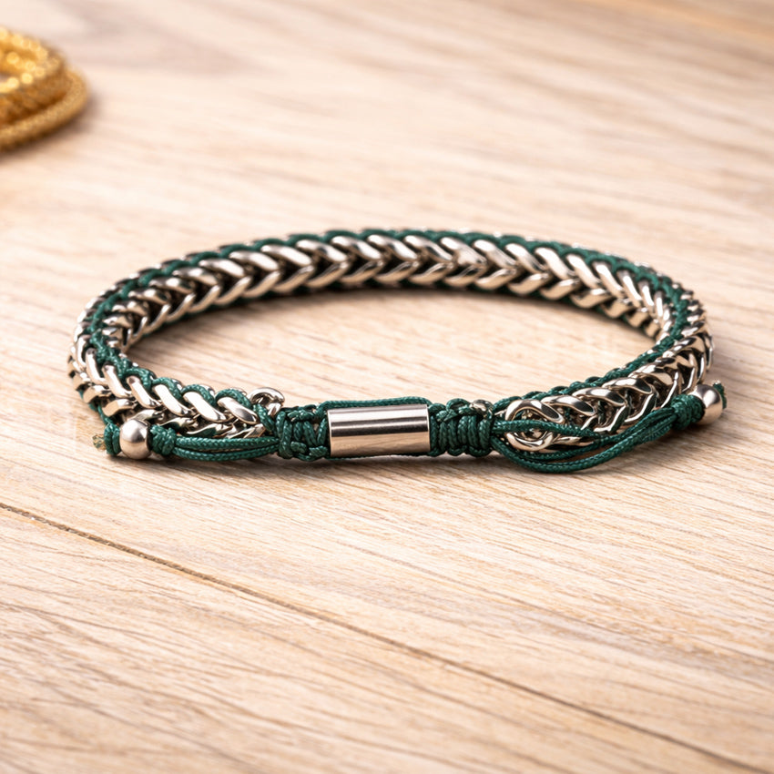 Men’s stainless steel curb-link bracelet with deep-green cord and steel centerpiece on wood surface