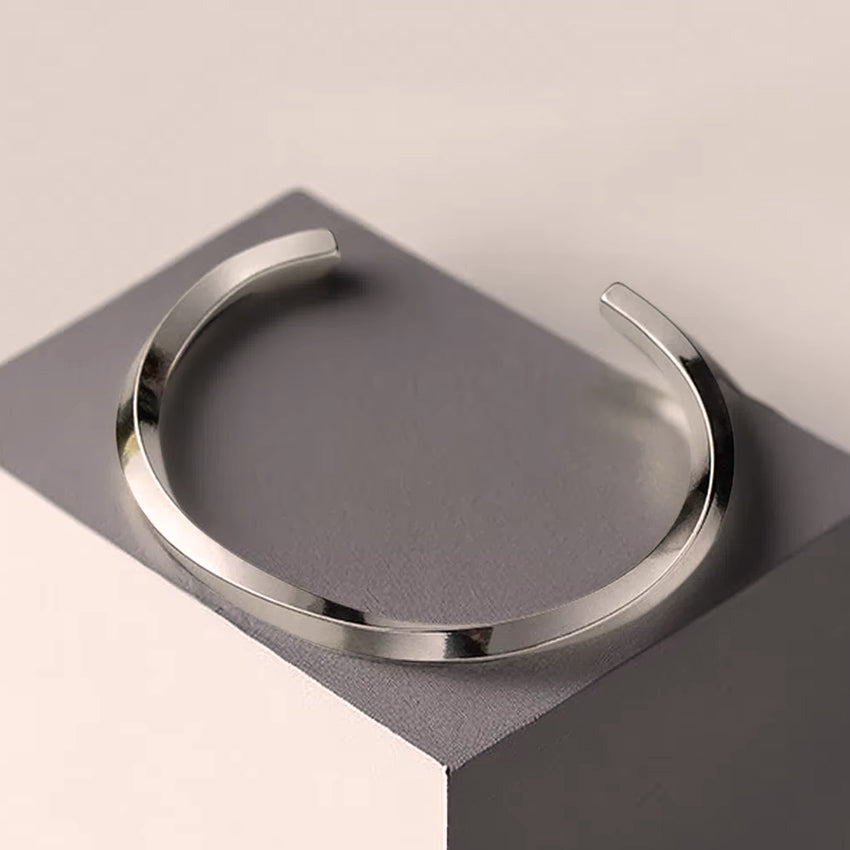 Minimal stainless steel open cuff bracelet on display, polished finish