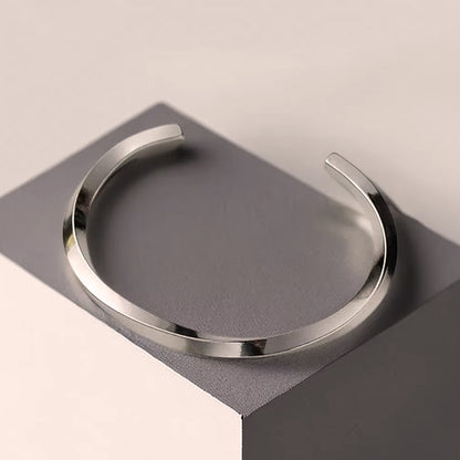 Minimal stainless steel open cuff bracelet on display, polished finish