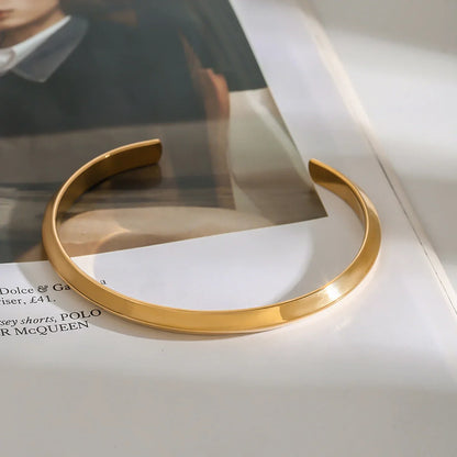 Gold-plated open cuff close-up showing smooth curvature and polished edge