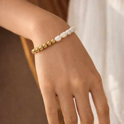 Pearl and gold sphere bracelet on wrist, stretch-fit design