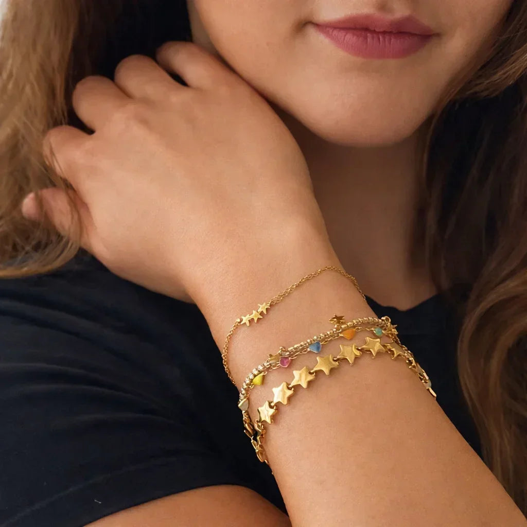Gold-plated star bracelet stacked on wrist, multicolor enamel accents