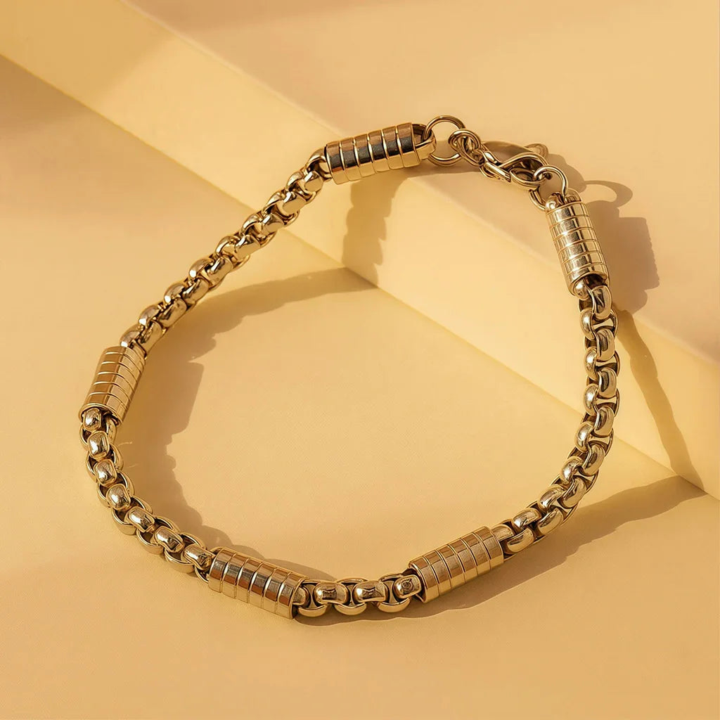 Gold-plated chain link bracelet flat lay, stainless steel with gold finish and barrel accents