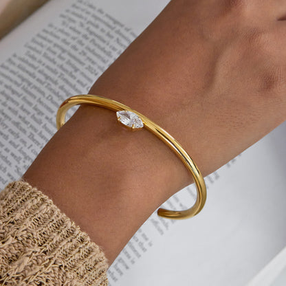 Marquise zircon open gold cuff bracelet on wrist, single marquise-cut clear zircon detail