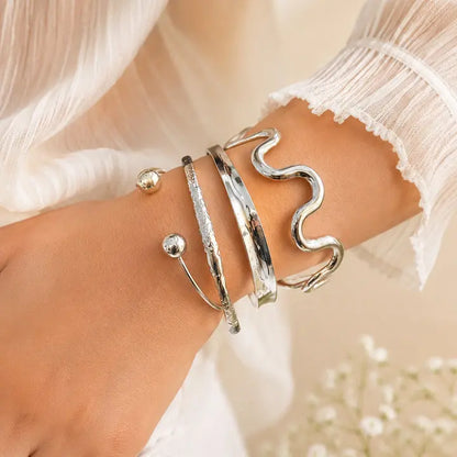 Close-up of a wrist wearing multiple silver bracelets with a soft background